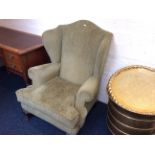 A green fireside wing backed armchair with oak clawed feet.