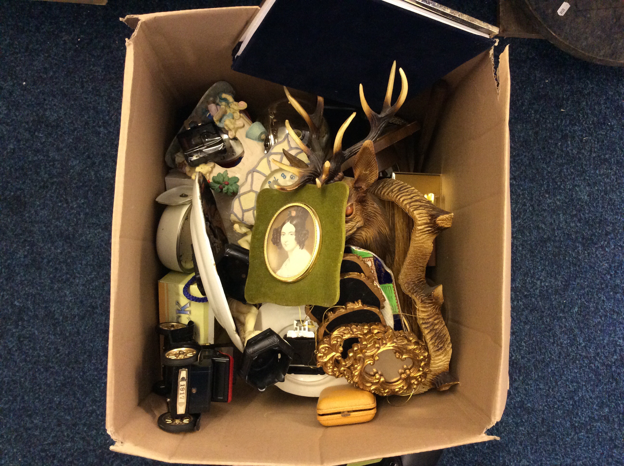 A box of assorted items including a set of mirror decorations, a deer wall hanging, a Tun 1917 toy