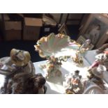 Four ceramic figurines, a ceramic candlestick with decorative figurines and gilding and a ceramic