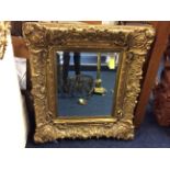 A square wall mirror with gilded Classical wooden frame.