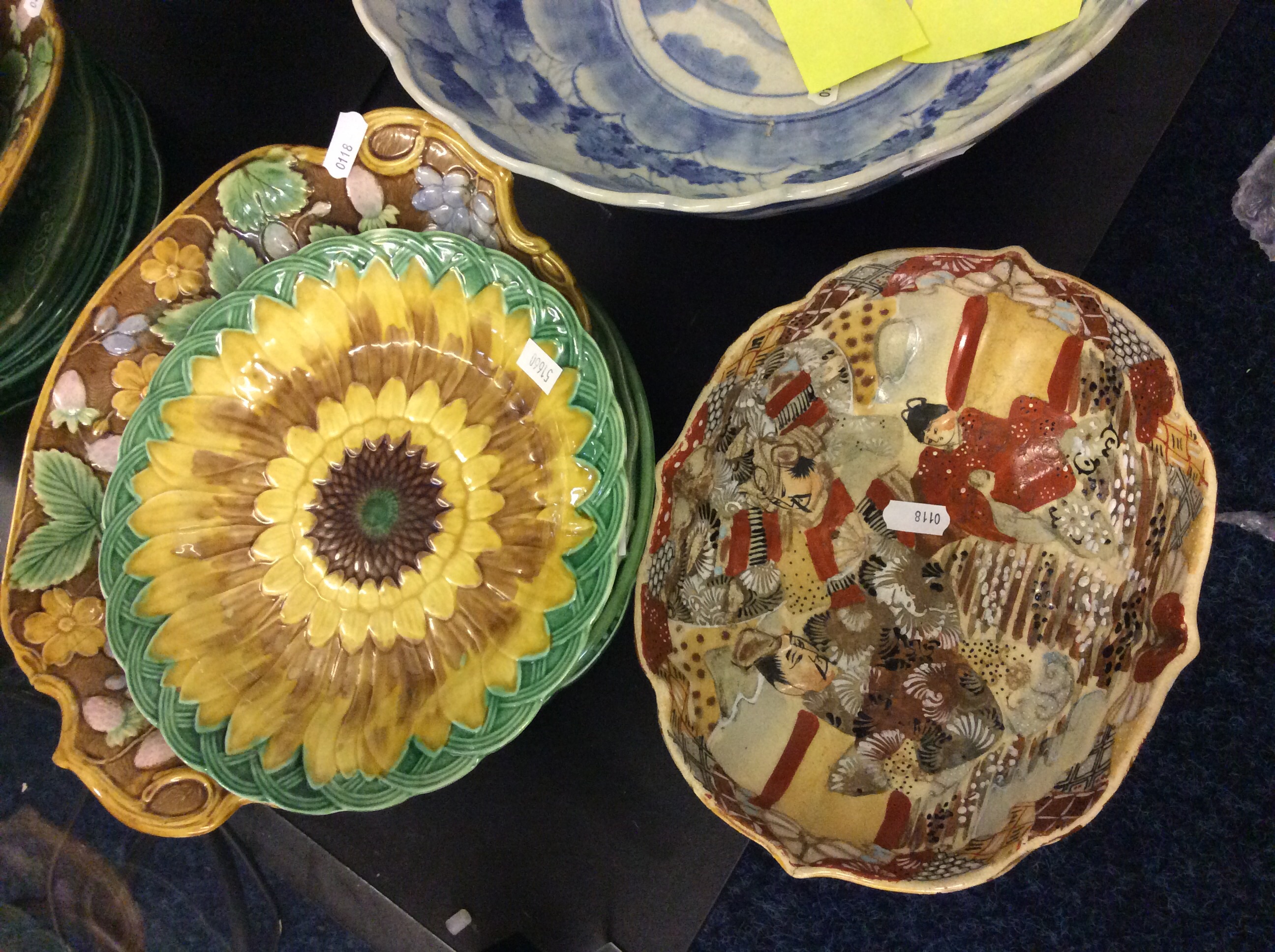 A set of green ceramic plates with sunflower design and an oriental dish.