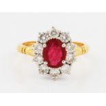 An 18ct yellow gold ruby and diamond cluster ring, set with a central oval cut ruby, measuring