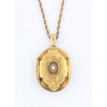 A Victorian locket, set with a central half pearl surrounded by foliage engraving, yellow metal