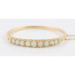 A late 20th Century Edwardian style 14ct yellow gold opal hinged bangle, set with eleven graduated