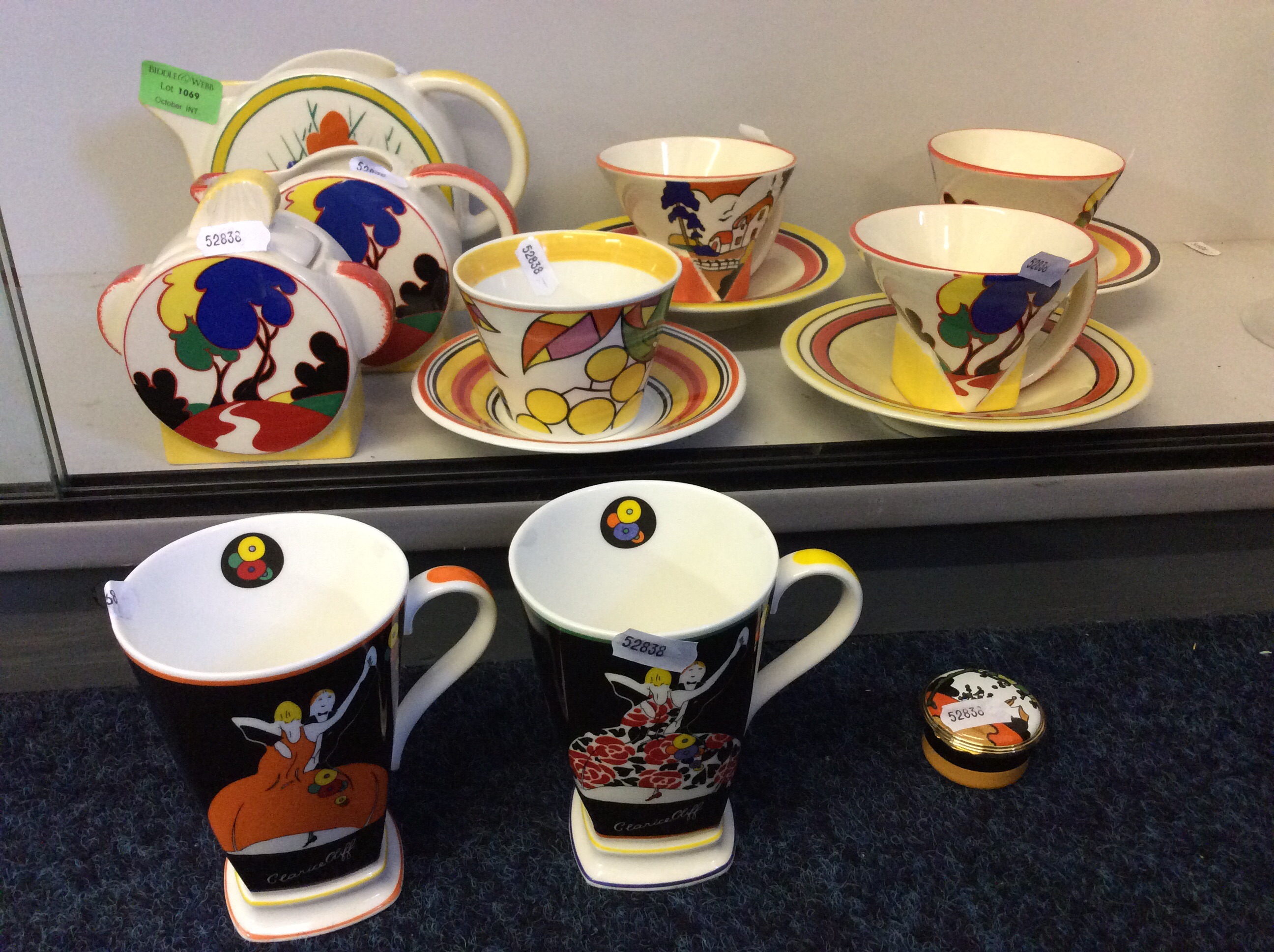 Two mugs, a set of four cups and saucers and a small box in the style of Clarice Cliff as well as