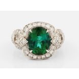 An 18ct white gold green tourmaline and diamond dress ring, set with a central oval cut green