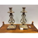 A pair of bronze candlesticks with scroll decoration.