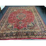 A large Persian Mashad rug with busy overall design all on red ground, length 385cm, width 295cm.