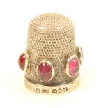 A silver thimble set above the rim with six amethyst coloured cabochon set stones, Birmingham 1894