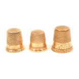 Three American gold thimbles, one with engraved frieze all with decorative rims. (3)