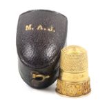 A Victorian gold thimble with an upper plain frieze over a wire work and dot geometric border, the