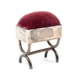 A silver pin cushion in the form of a rectangular stool on curved cross frame end supports, London