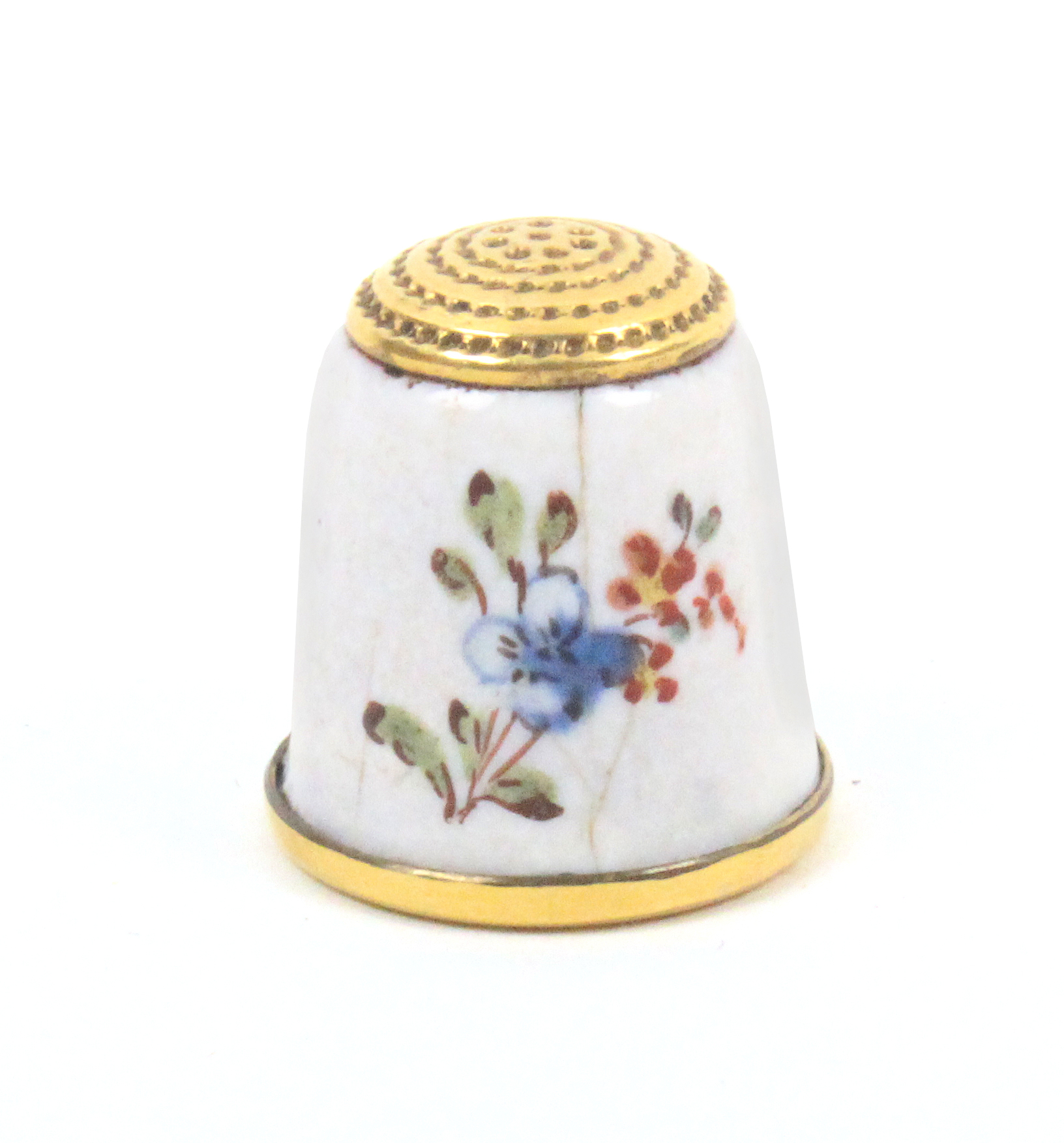 An enamel thimble the white ground painted with single and multiple flowers, cracked and