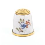 An enamel thimble the white ground painted with single and multiple flowers, cracked and