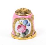 An 18th Century South Staffordshire enamel thimble the pink ground painted with a floral panel on