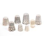 Eight silver thimbles comprising a cable style example, another with raised and pierced rim, an