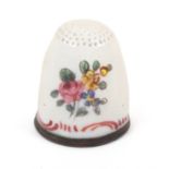 An 18th Century South Staffordshire enamel thimble painted with flowers and flower sprays above a