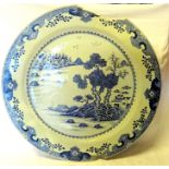 A late 18th/early 19th Century Chinese Charger decorated in blue and white with a river landscape.