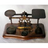 A set of brass Postal Scales and weights on a wooden base.