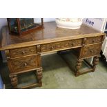 An oak carved pedestal desk with inset leather top.