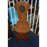 A 19th century oak hall chair with central decorat