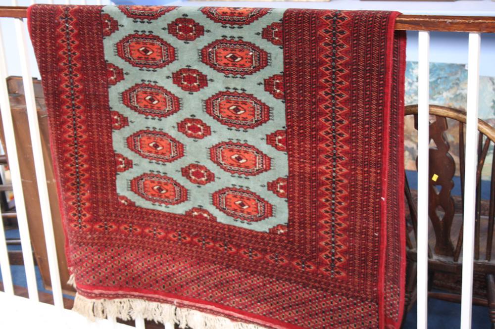 A Pakistani Bokhara rug, the pistachio green ground covered in guls highlighted in madder red, ivory