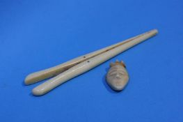 A 1920's Carved tribal ivory mask pendant, and a pair of glove stretchers