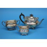 A silver three piece tea set supported on ball fee