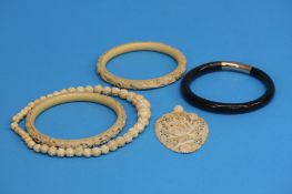Two ivory bangles, a pierced ivory pendant, an ivo
