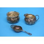 A silver tea strainer, a silver sugar bowl and a s