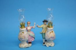 A pair of Continental porcelain figural oil lamps 25cm height