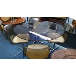 A 1970's smoked glass circular table with chrome base and a set of four plastic tub chairs. 110 cm