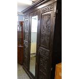 A heavily carved oak triple door wardrobe, 165 x 210cm