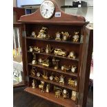 A collection of brass novelty clocks in a mahogany cabinet