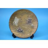 A Japanese mixed metal charger, decorated with figures in a landscape. 28 cm diameter
