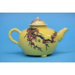 A famille rose teapot and cover, the yellow ground with prunus, trees and branches. 18.5 cm wide