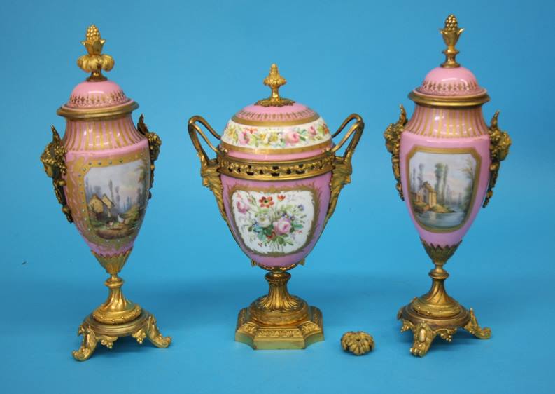 A Continental porcelain three piece garniture, each vase decorated on a pink Sevres style ground