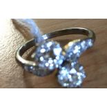 A platinum set diamond crossover ring with diamond set shoulders