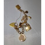 A gold charm bracelet with various charms to inc lighter, dolphin, notes,