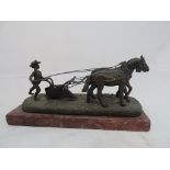 A Russian-style bronze of a man ploughing with two horses on marble base