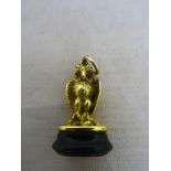 An 18ct unhallmarked model of an owl set with cabochon ruby eyes seated on a perch,