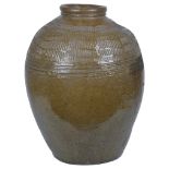 A Large Chinese Glazed Pottery Jar: Ming Dynasty: Entirely covered in an olive green glaze.