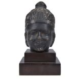 An Antique South-East Asian Stoneware Sculpture: Modelled as a Buddha head. On a later wooden base.