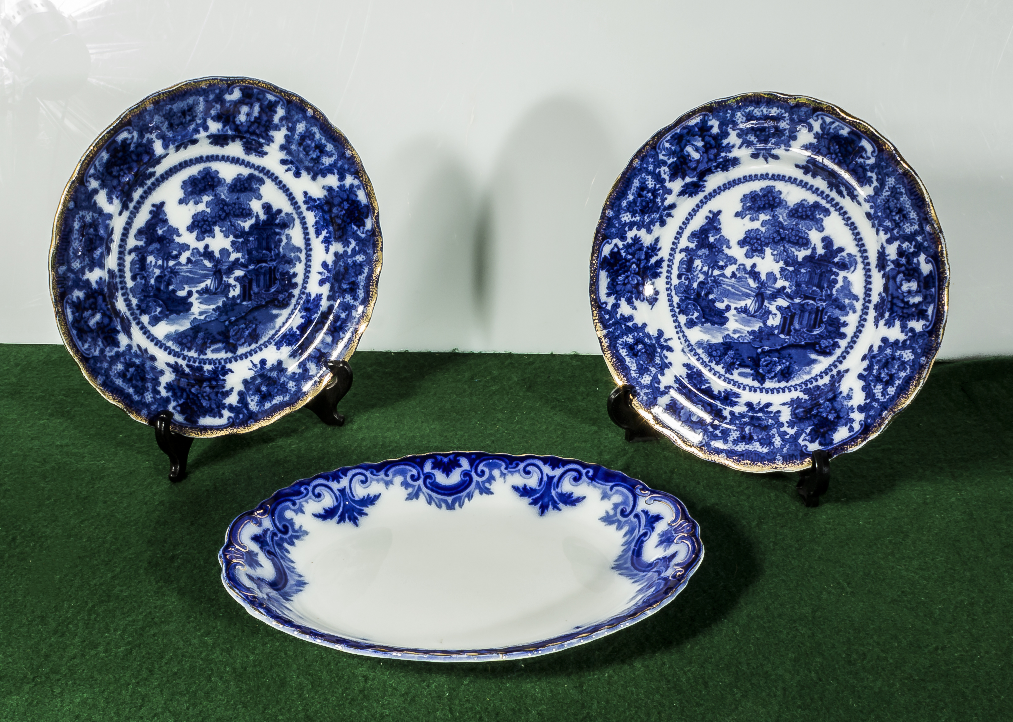 A pair of flow blue plates and an oval serving dish