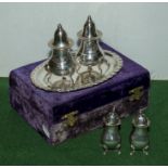 A silver plated cruet set in case and one other plated salt and pepper