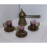 A Middle Eastern coffee pot and three cups and saucers