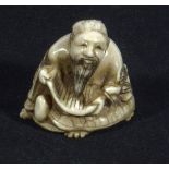 A Japanese ivory netsuke man reading a scroll, signed