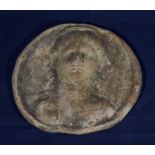 A terracotta roundel of a lady which was excavated at Cirencester, 1st-2nd century AD. 14cm