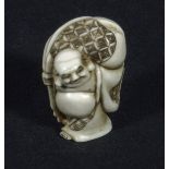 A Japanese ivory netsuke, Hotei carrying a large sack, signed