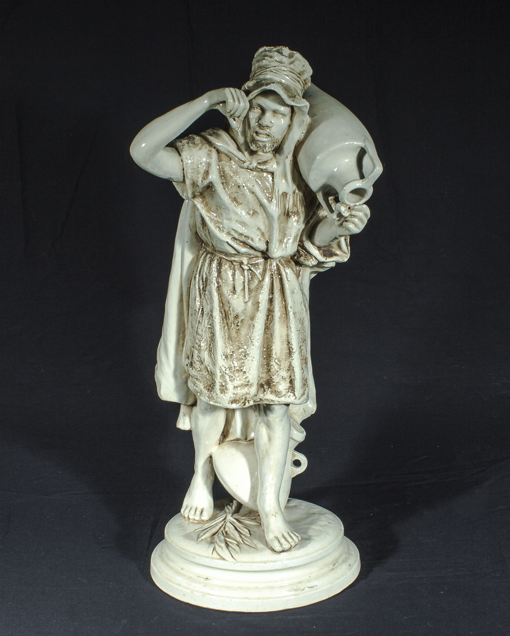 A large glazed pottery figure of a water carrier, 56cm tall